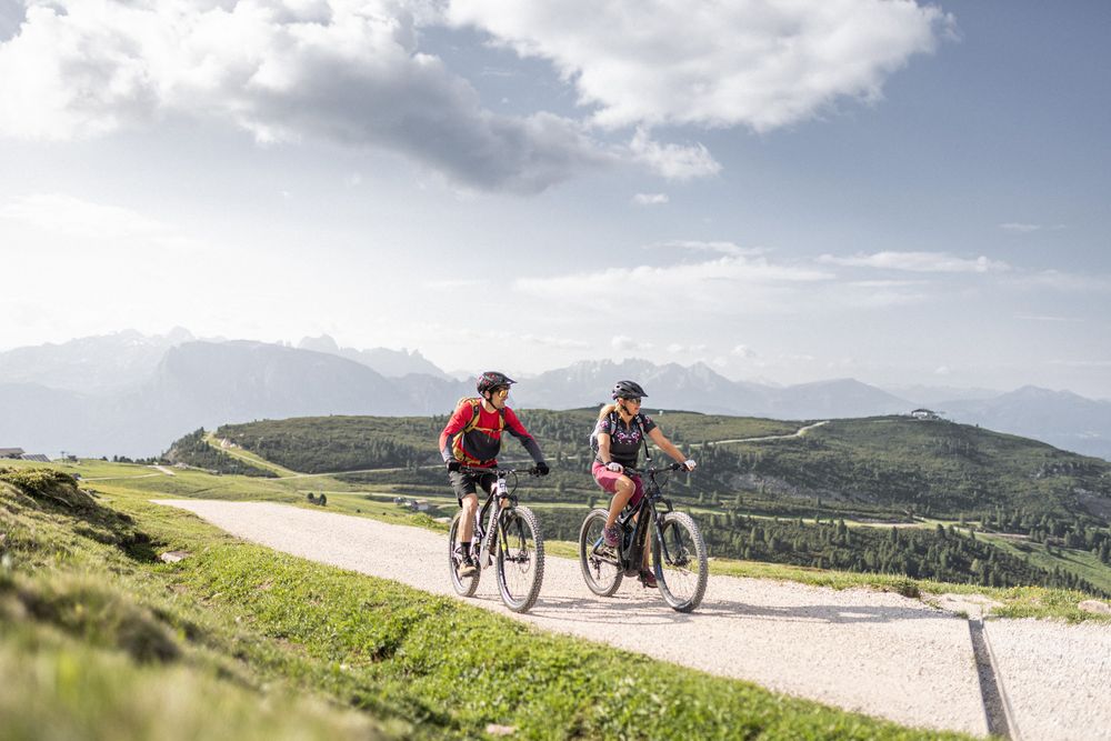 Zwei Radfahrer fahren auf einem Bergweg bei klarem Wetter.