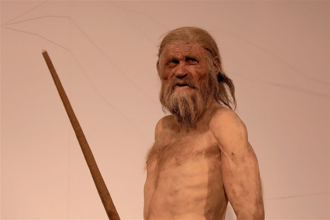 Reconstructed model of an ancient man with a beard holding a wooden spear
