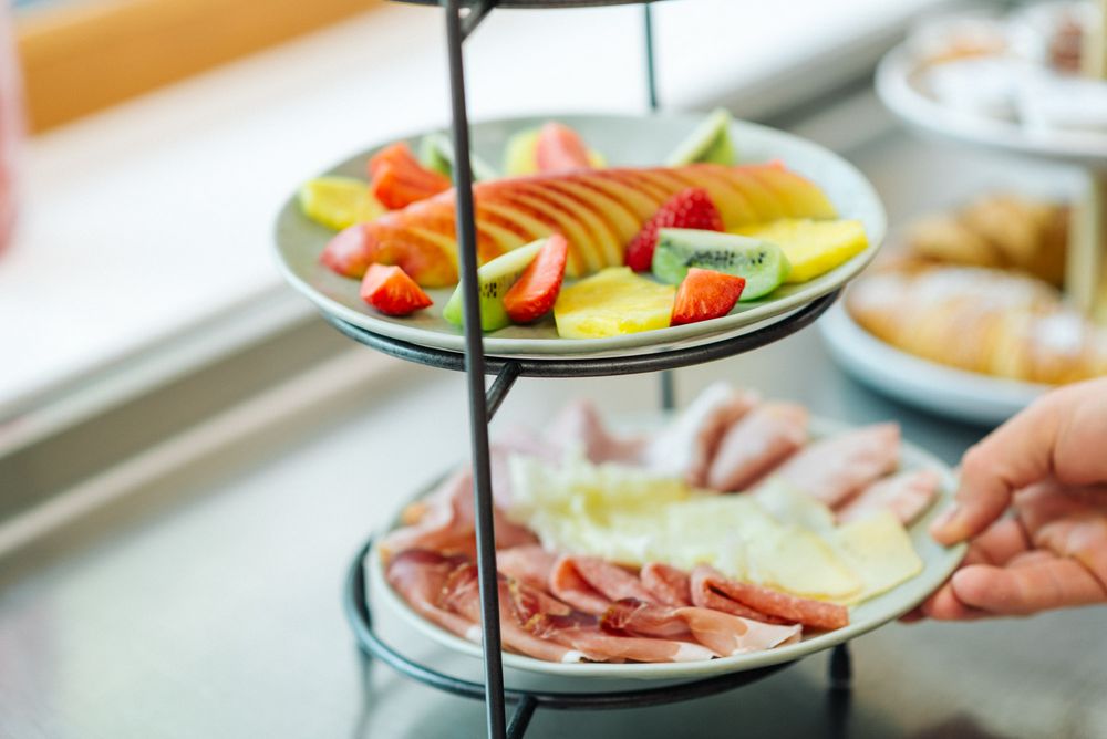 Zweistöckige Servierplatte mit frischem Obst und Aufschnitt.