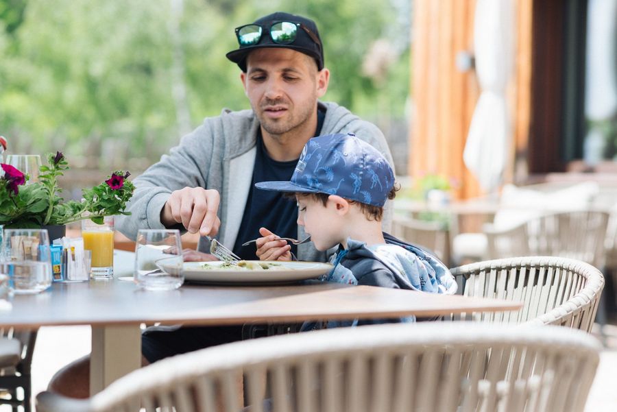 Mann und Kind essen gemeinsam draußen am Tisch.