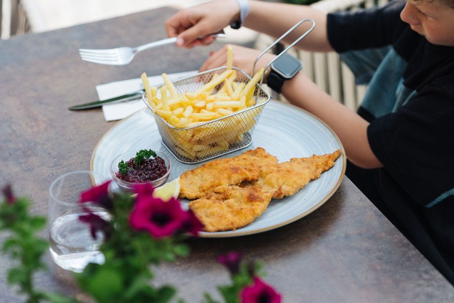 Kind mit Schnitzel, Pommes und Preiselbeersoße auf einem Teller