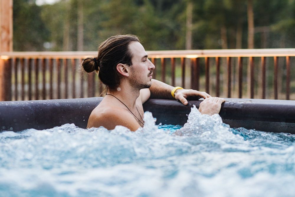 Mann mit Pferdeschwanz entspannt im Whirlpool im Freien