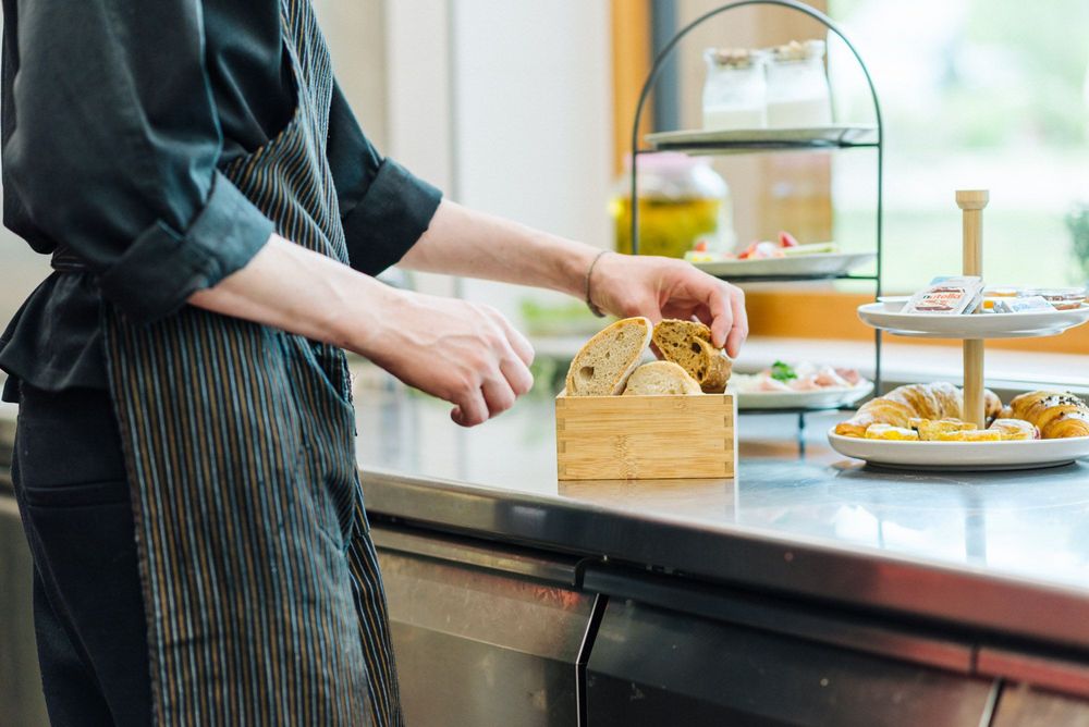 Person legt Brotscheiben in einen Brotkorb in einer Küche