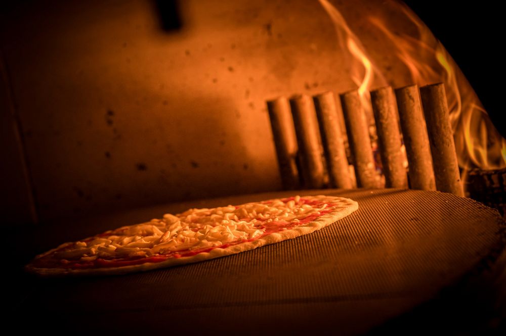Pizza backt im Steinofen über Holzfeuer