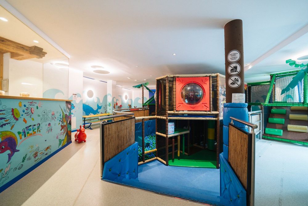 Kinderspielbereich mit Bällebad, Klettergerüst und bunten Wandgemälden in einem Innenraum
