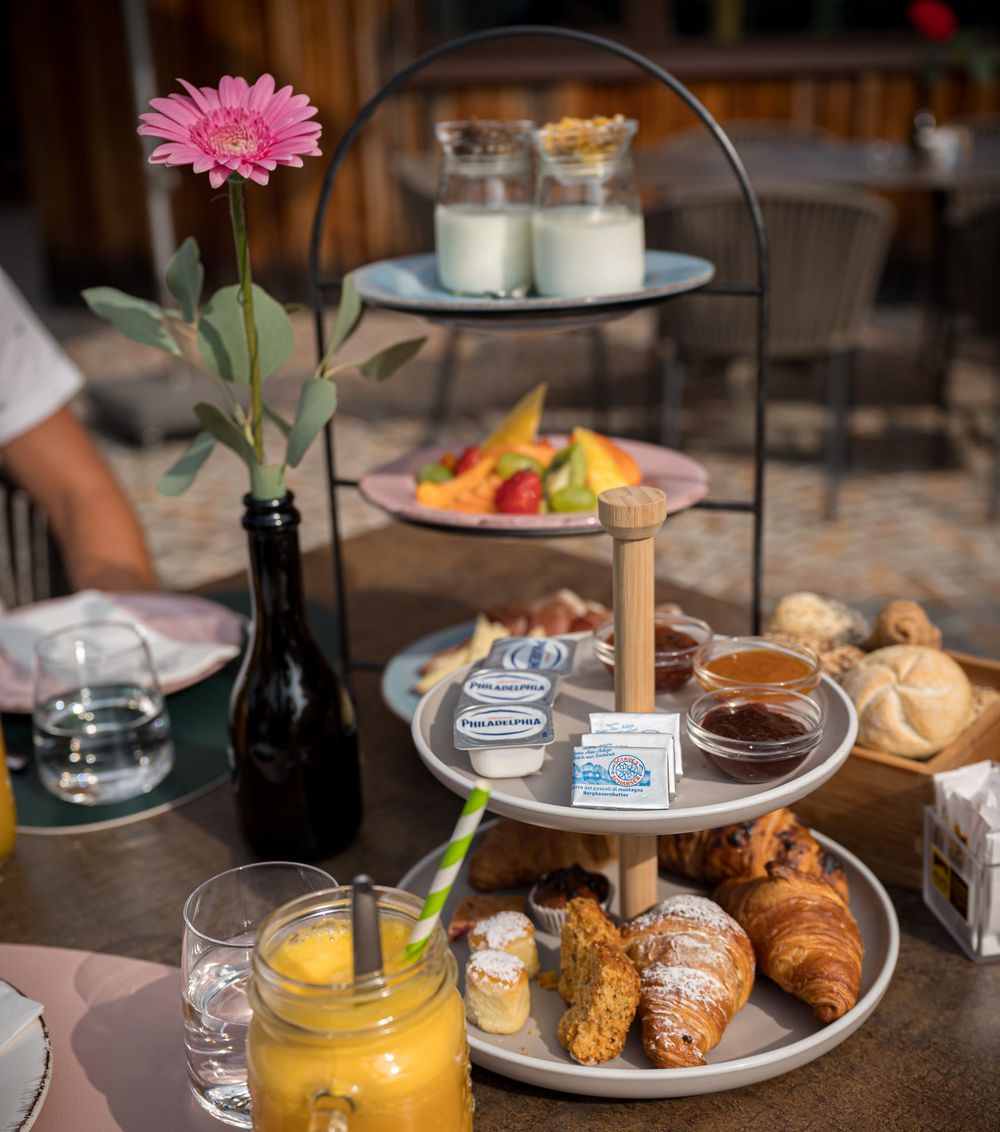 Frühstück mit Gebäck, Obst, Jogurt und Orangensaft auf einem Tisch im Freien