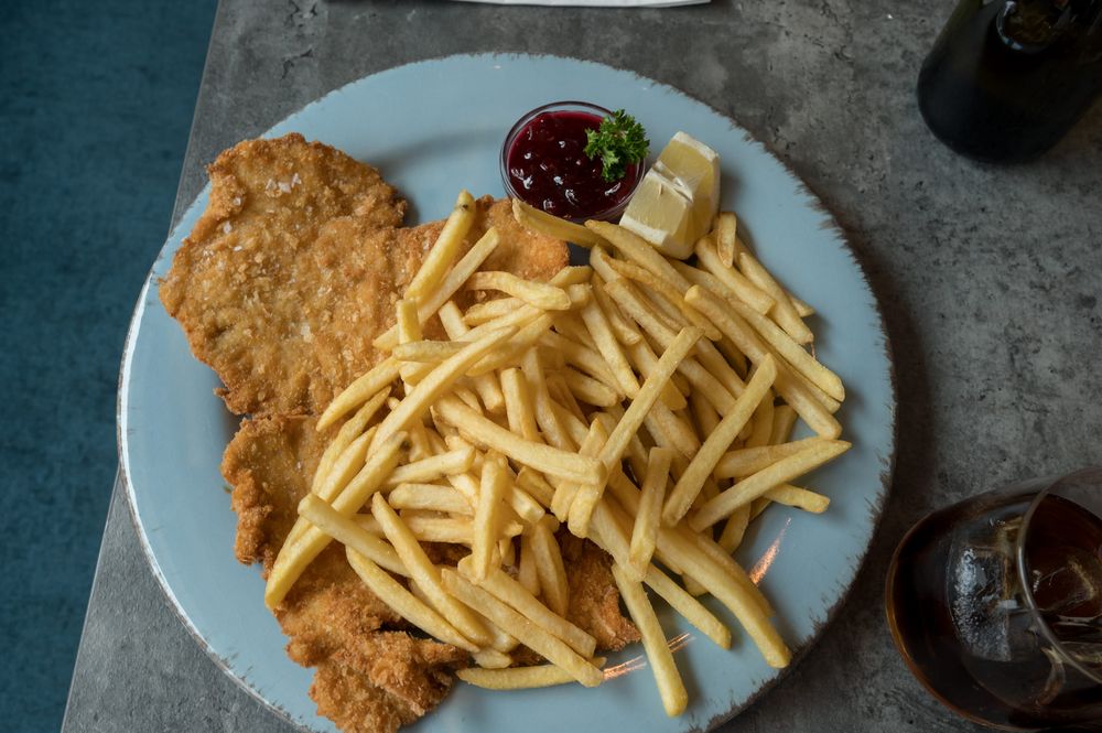 Schnitzel mit Pommes, Zitronenscheibe und Preiselbeersoße auf einem Teller