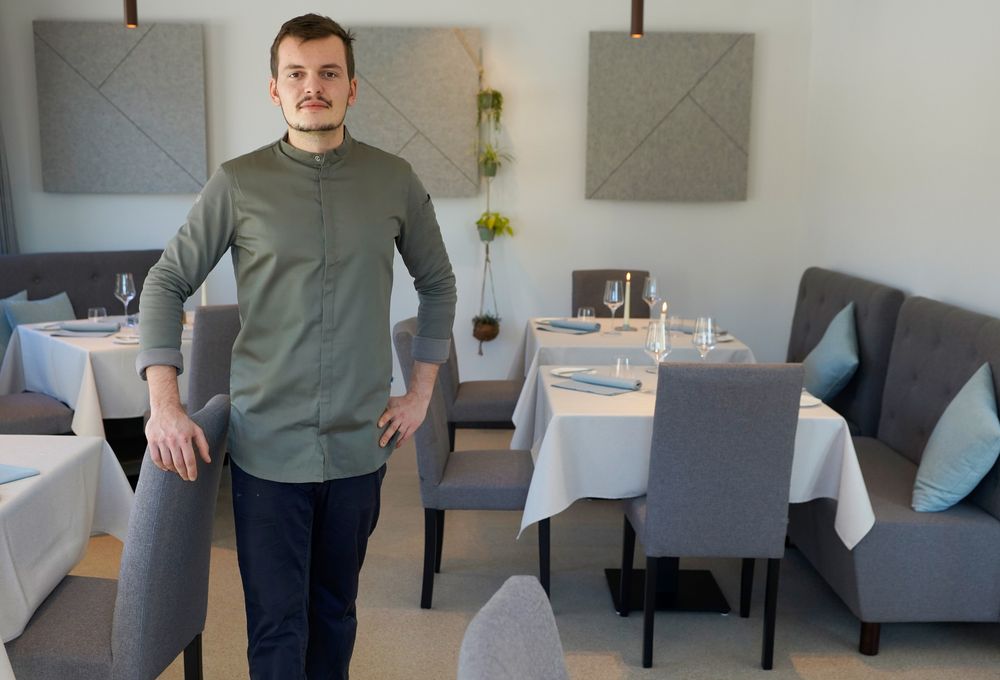 Mann in Kochjacke in elegantem Restaurant mit gedeckten Tischen